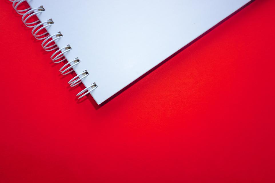 white spiral notebook on red surface